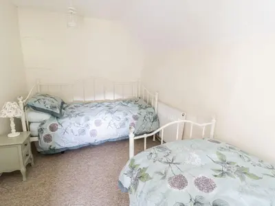 a bedroom with a bed and a table with a lamp at Tan Y Garth Cottage in Corwen
