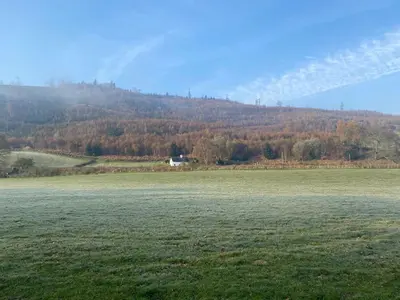 a field of grass with a hill in the background at Tan Y Garth Cottage in Corwen