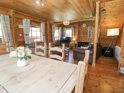 a living room with a table with a vase of flowers at Sun View Lodge in Llanbedr