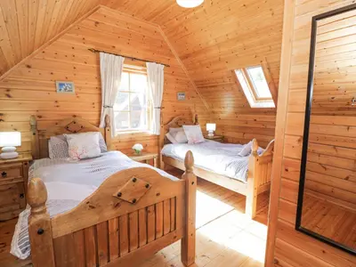 a bedroom with two beds in a log cabin at Sun View Lodge in Llanbedr