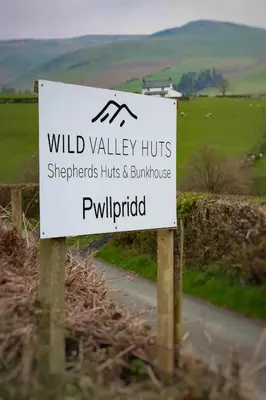 a sign for wild valley huts in a field at Wild Valley Bunkhouse in Llanrhaeadr-ym-Mochnant