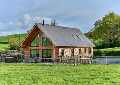 a large wooden house in the middle of a field at Holly Lodge in Welshpool