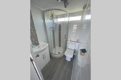 a bathroom with a toilet and a sink and a mirror at Modern Funky Private Chalet at the Beach in Tywyn