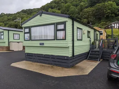 a green and black tiny house in a parking lot at Gloria Stay - Aberystwyth Caravan in Aberystwyth