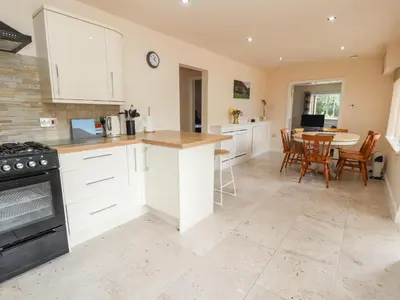 a kitchen with white cabinets and a table with chairs at Awel Y Berwyn in Oswestry