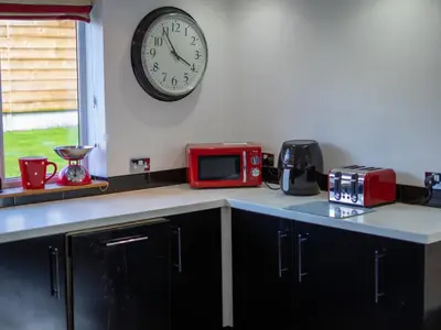 a kitchen with a microwave and a clock on the wall at The Old Post Office in Llandrindod Wells