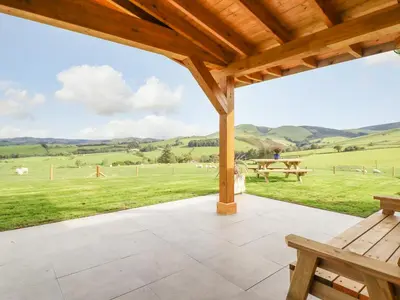 a porch with a bench and a view of a field at Bacheiddon Log Cabin in Machynlleth