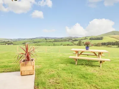 a picnic table in the middle of a field at Bacheiddon Log Cabin in Machynlleth