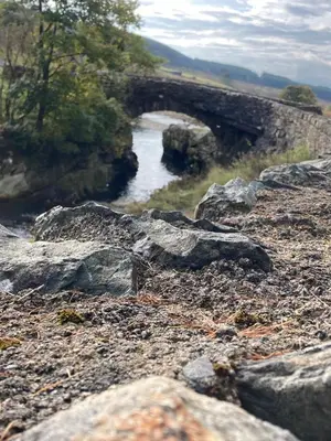 a stone bridge over a river with rocks at Penystryd in Trawsfynydd