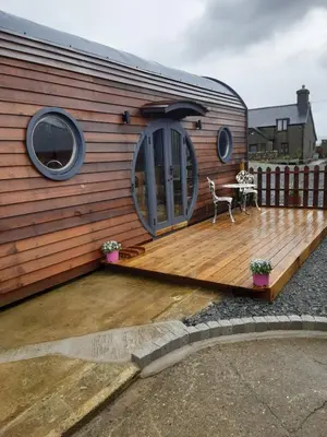 a house with a wooden deck with a table on it at Penystryd in Trawsfynydd