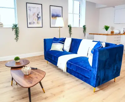 a blue couch in a living room with a table at Shrewsbury apartments by BEVOLVE - Free Parking in Shrewsbury