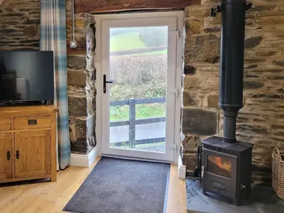 a wood stove in a room with a door at The Granary in Llanddeiniol