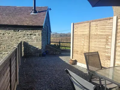 a patio with a table and chairs next to a building at The Granary in Llanddeiniol