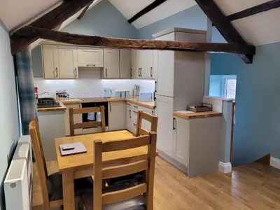 a small kitchen with a wooden table and chairs at The Granary in Llanddeiniol