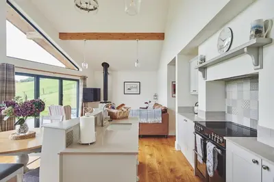 a kitchen with white cabinets and a living room at Shepherds Rest in Llandyssil
