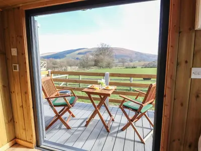 a patio with a table and chairs on a deck at Claerwen in Llandrindod Wells