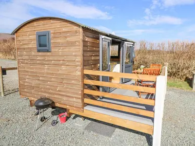 a wooden tiny house with a porch and chairs at Elan in Llandrindod Wells