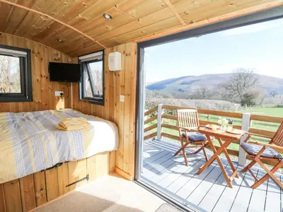 a bedroom with a bed and a table on a deck at Elan in Llandrindod Wells