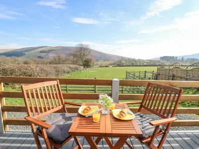 a wooden table and two chairs on a deck at Elan in Llandrindod Wells