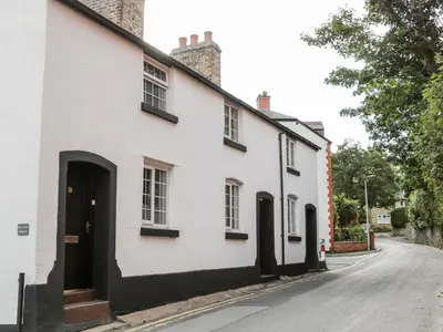 a white house with black windows and a street at Cuddfan in Llangollen