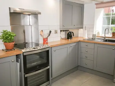 a kitchen with gray cabinets and a stove top oven at Cuddfan in Llangollen
