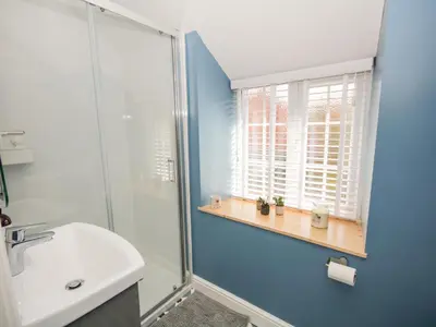 a bathroom with a glass shower and a sink at Cuddfan in Llangollen