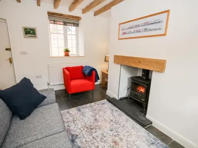 a living room with a fireplace and a red chair at Cuddfan in Llangollen