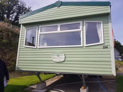 a green tiny house on display in a yard at D19 in Aberystwyth