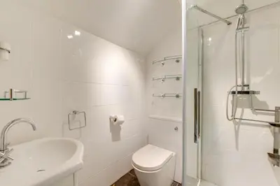 a white bathroom with a toilet and a shower at 6 Bed in Barmouth oc-bow245 in Fairbourne