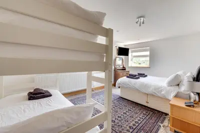 a bedroom with two bunk beds and a television at 6 Bed in Barmouth oc-bow245 in Fairbourne