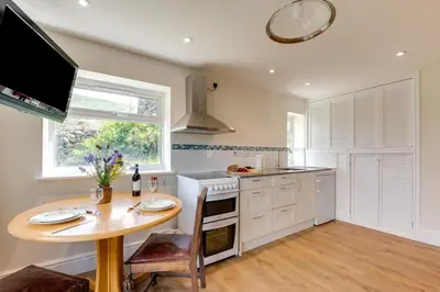 a kitchen with a table and a stove and a window at 6 Bed in Barmouth oc-bow245 in Fairbourne