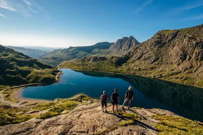 three people standing on top of a mountain overlooking a lake at 6 Bed in Barmouth oc-bow245 in Fairbourne