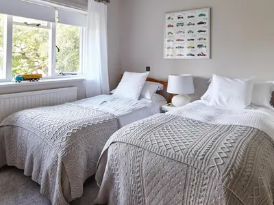 two beds in a white room with a window at Green Acres in Llangollen