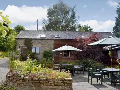 a patio with tables and umbrellas in front of a building at Jinney Ring in Leintwardine