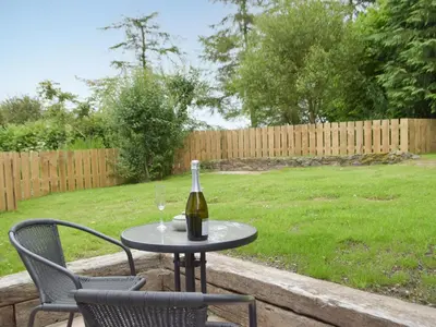 a table with a bottle of wine and a glass at Llain Cottage in Llanina