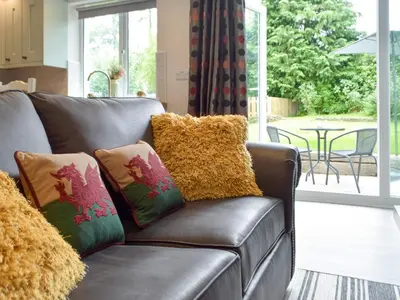 a brown leather couch with colorful pillows in a living room at Llain Cottage in Llanina