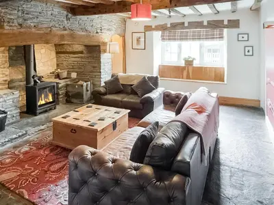 a living room with a leather couch and a fireplace at Lower Farm in Llanfihangel Rhydithon