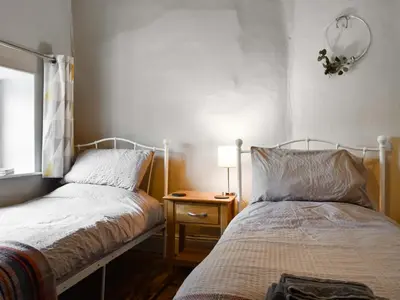 a bedroom with two beds and a table with a lamp at Lower Farm in Llanfihangel Rhydithon