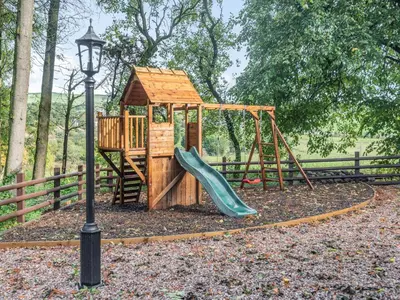 a wooden playground with a slide and a play structure at Groudd Hall in Cerrigydrudion