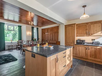 an open kitchen with wooden cabinets and a dining room at Groudd Hall in Cerrigydrudion