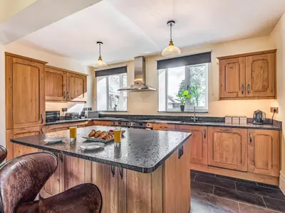 a kitchen with wooden cabinets and a large island at Groudd Hall in Cerrigydrudion