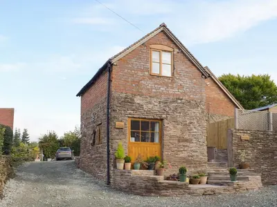 a brick house with a yellow door and potted plants at The Granary in Clee Saint Margaret