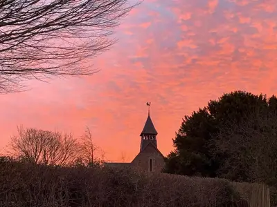 a church steeple with a sunset in the sky at The Granary in Clee Saint Margaret