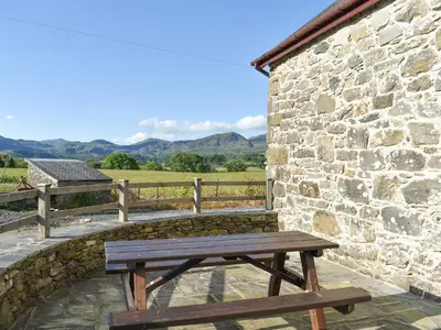 a wooden bench sitting outside of a stone building at Stabal Rhoswen in Ffestiniog