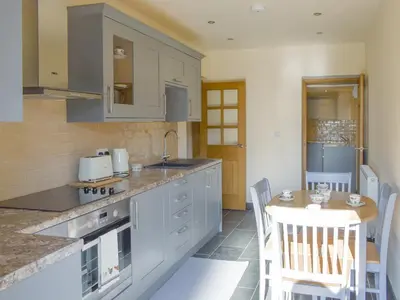 a kitchen with a counter and a table with chairs at Stabal Rhoswen in Ffestiniog