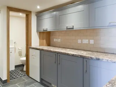 a kitchen with gray cabinets and a toilet at Stabal Rhoswen in Ffestiniog