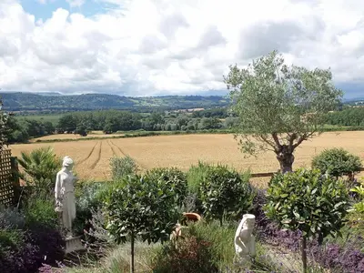 a garden with statues in the middle of a field at Hop Kiln Barn in Staunton on Wye
