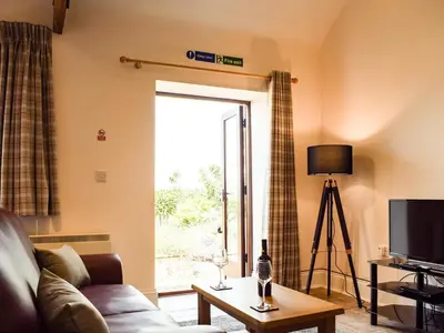 a living room with a couch and a sliding glass door at Hop Kiln Barn in Staunton on Wye