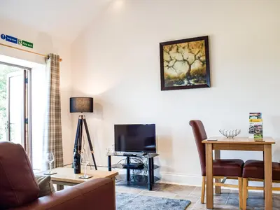 a living room with a couch and a television at Hop Kiln Barn in Staunton on Wye