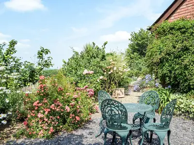 a table and chairs in a garden with flowers at Hop Kiln Barn in Staunton on Wye
